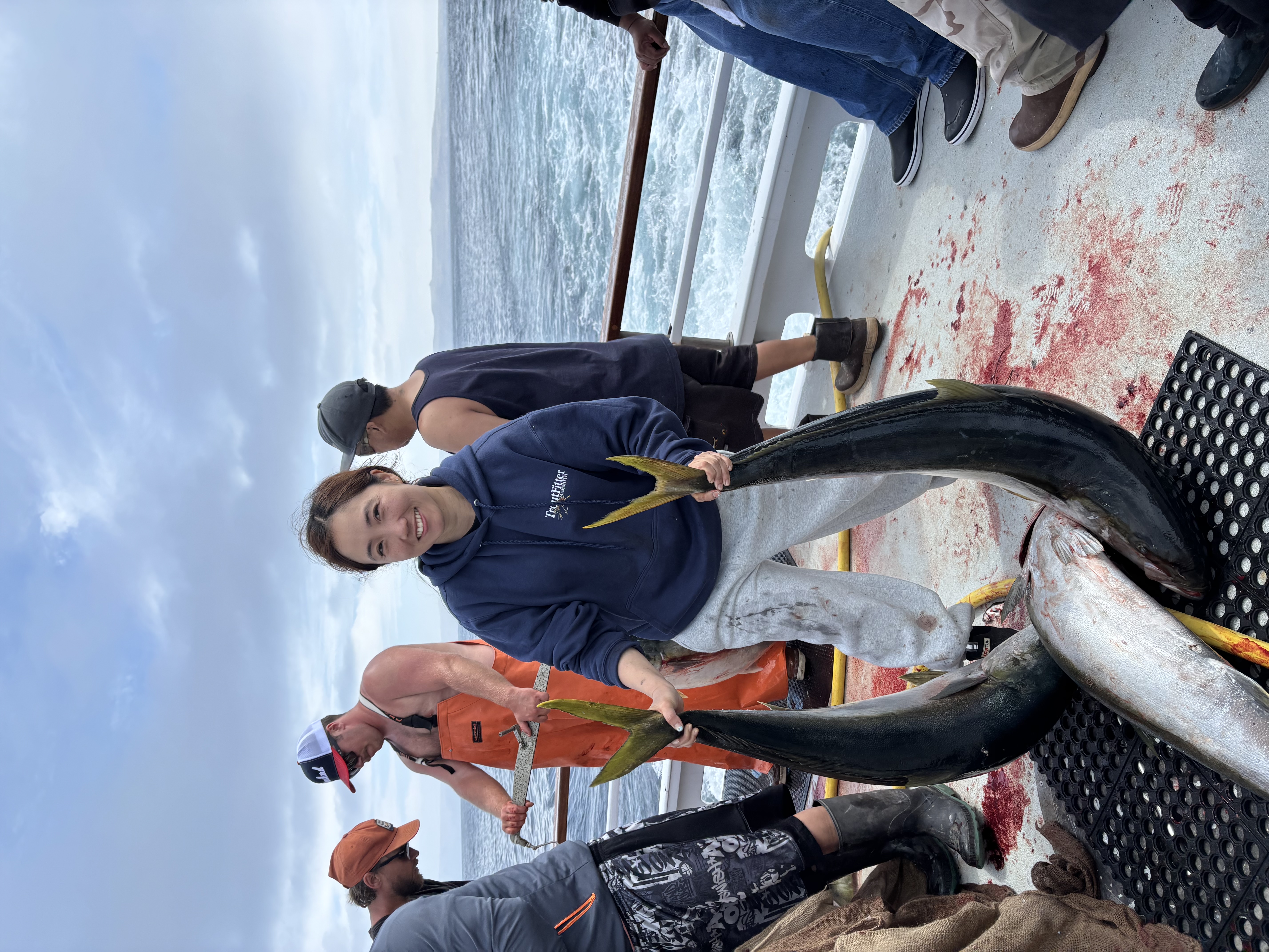 Tiffany Kim holding two yellowtail on a deep sea fishing boat